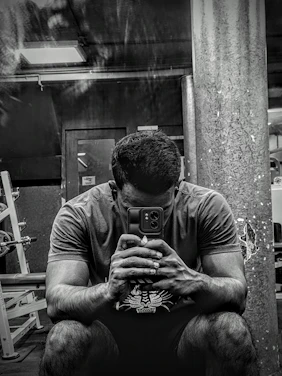 A modern gym with equipment and a person checking costs on a smartphone.