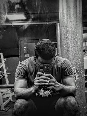 A friendly fitness coach smiling while holding a phone, ready to assist clients.