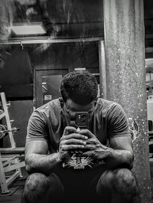 A modern gym with equipment and a person checking costs on a smartphone.
