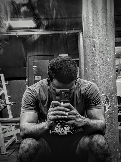 A person using a smartphone app to follow a personalized workout plan in a bright gym setting.