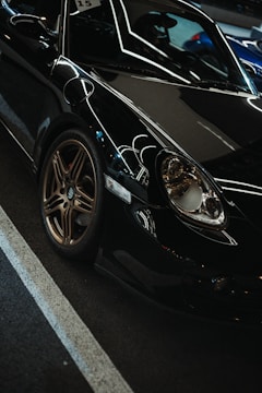 Luxury black and gold painted sports car in a dark studio setting highlighting glossy reflections