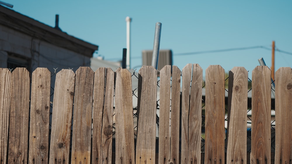 a close up of a wooden fence with a building in the background