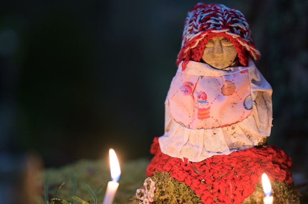 a close up of a candle with a doll on it