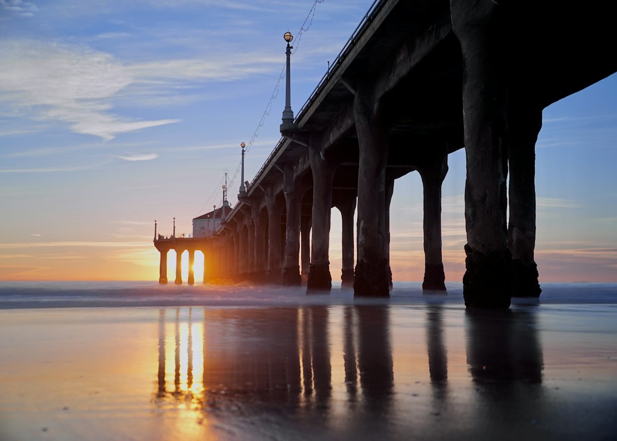 The sun setting at the end of a pier over the ocean