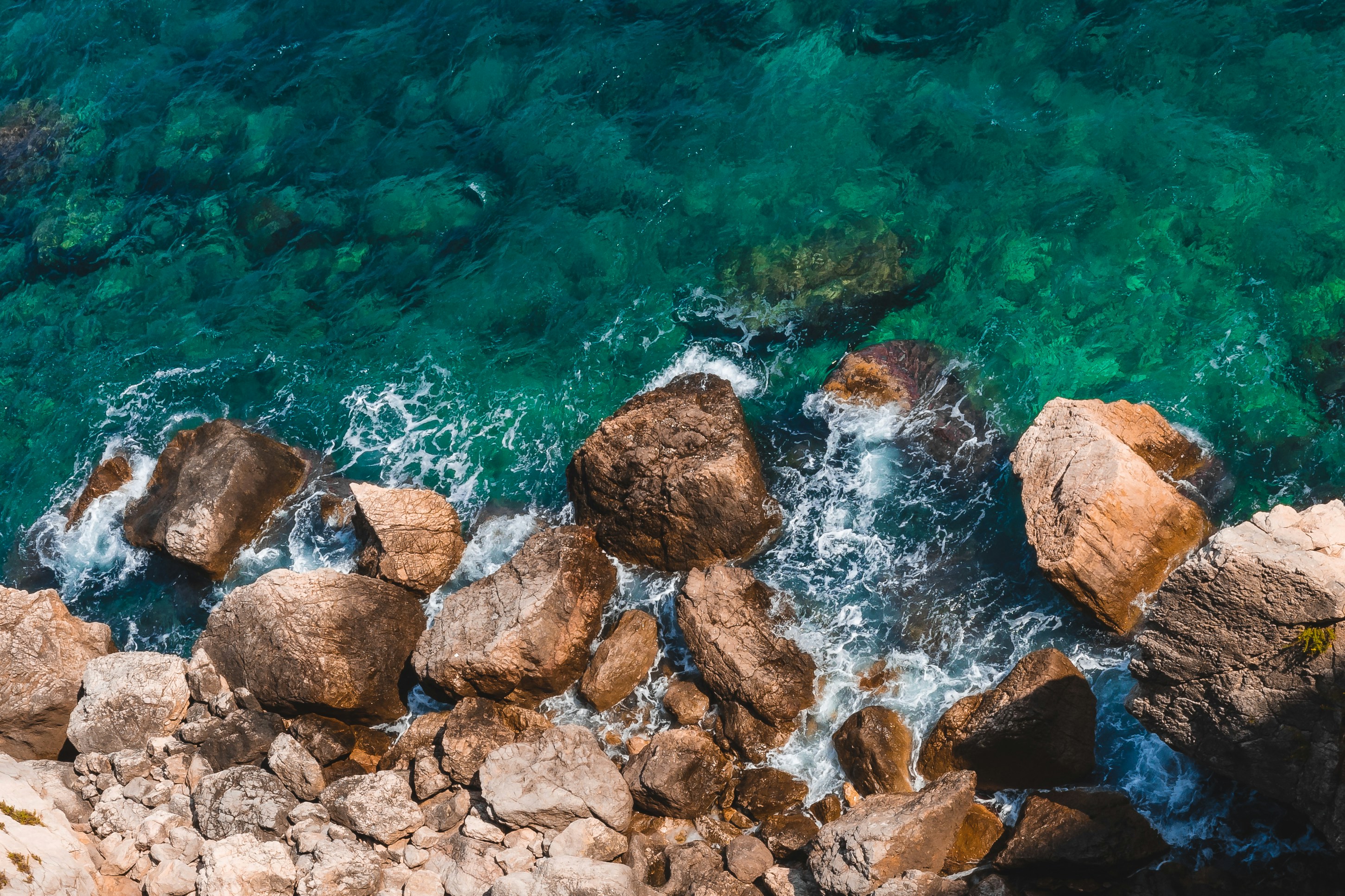 an aerial view of a rocky beach with clear blue water, 