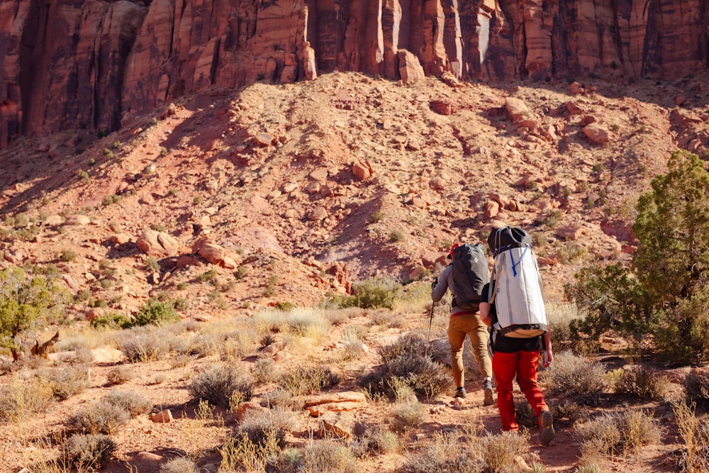 a couple of people with backpacks walking in the desert