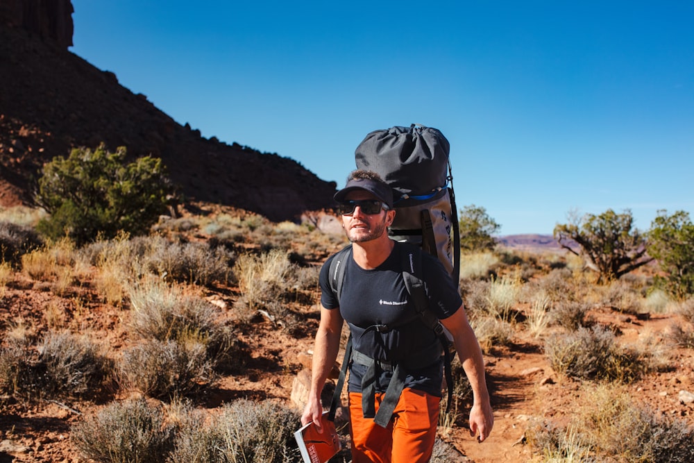 a man with a backpack and a camera in the desert