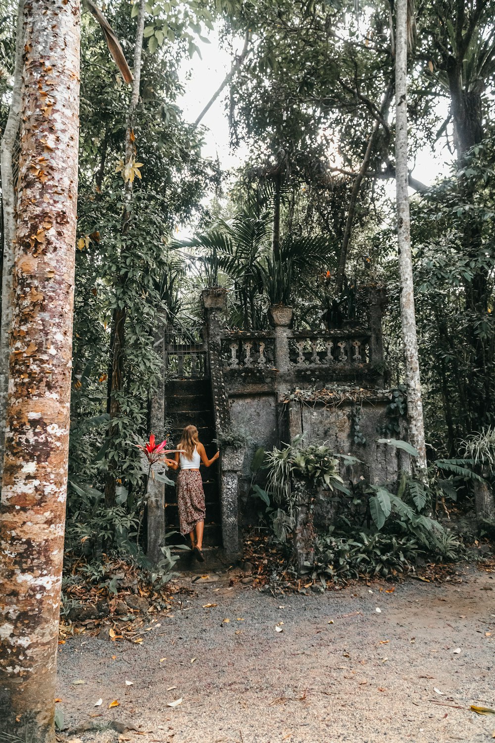 a woman standing in front of a stone structure surrounded by trees