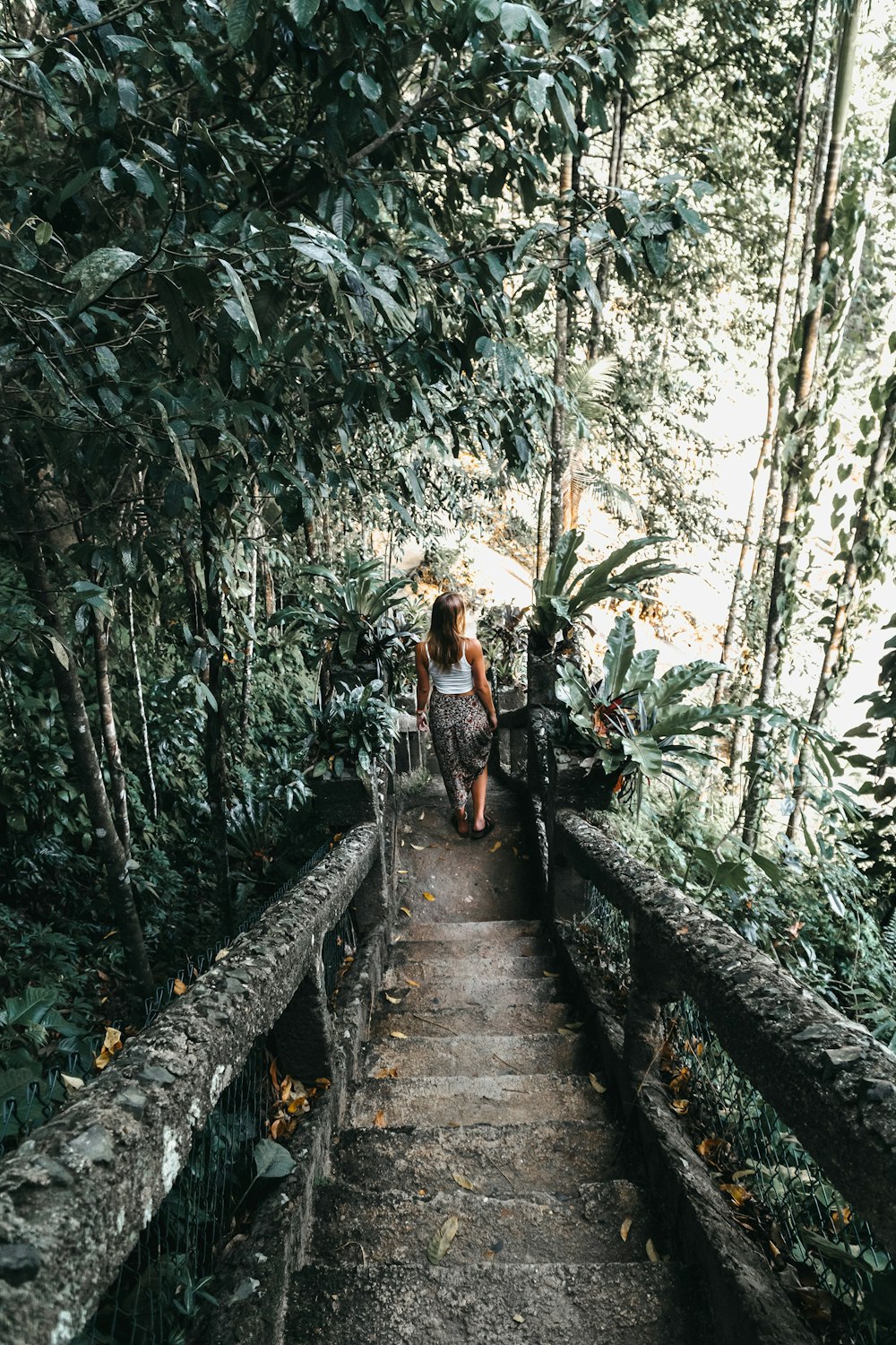 a woman walking down a path in the jungle