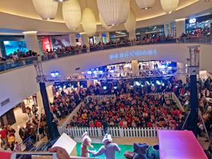 A vibrant live streaming setup inside a bustling shopping mall with hosts engaging the audience.