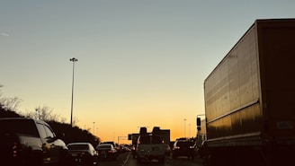 A highway scene with trucks on the road at sunset.