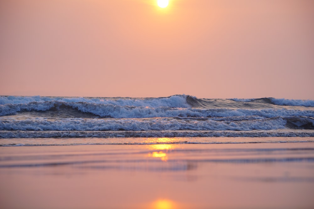 the sun is setting over the ocean waves