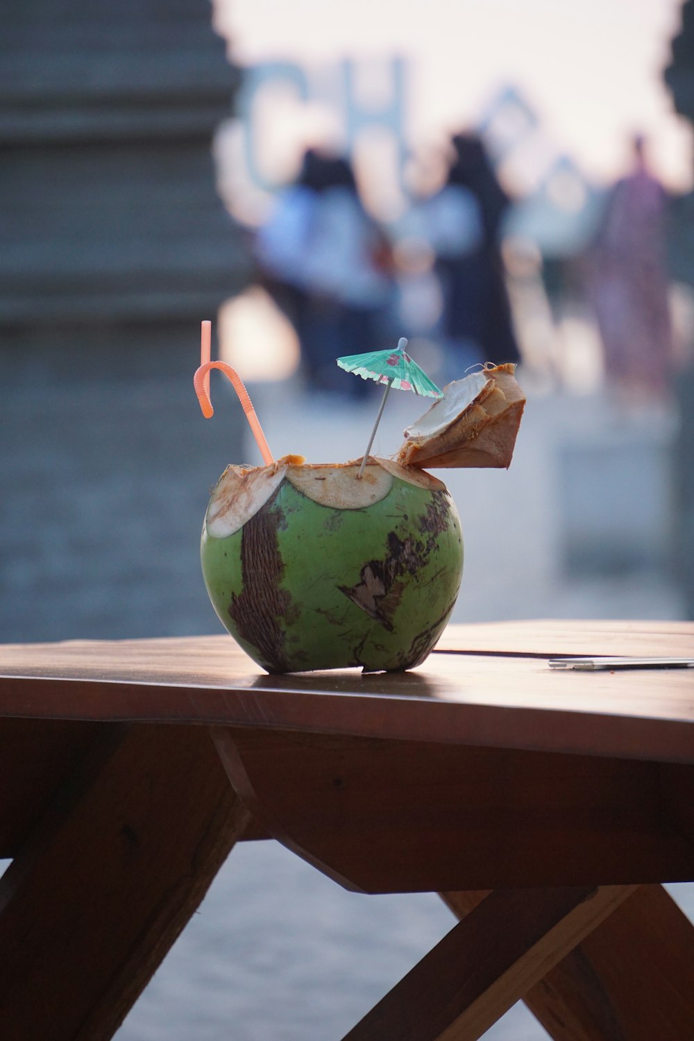 a green coconut drink sitting on top of a wooden table