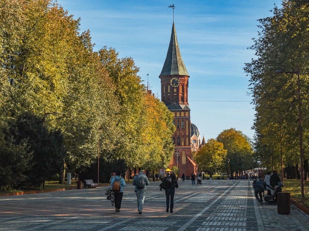 a group of people walking down a street next to a tall tower