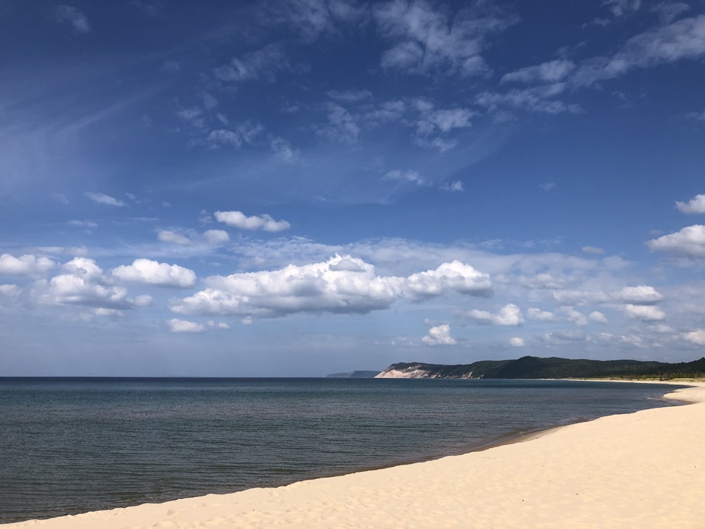 a sandy beach next to the ocean under a blue sky