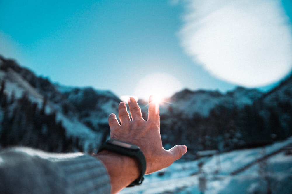 a person's hand reaching up into the sky