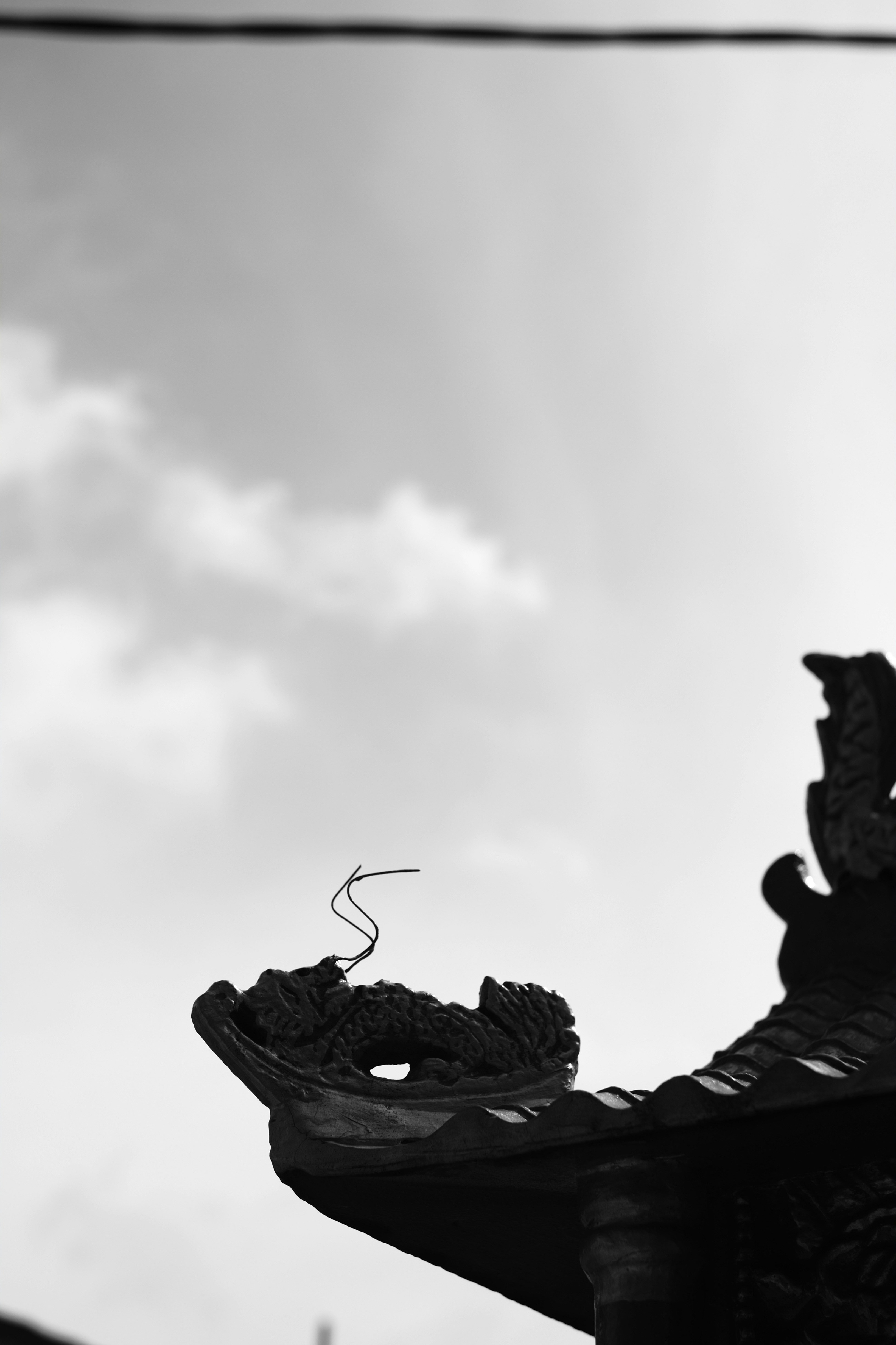 a black and white photo of a dragon on a roof