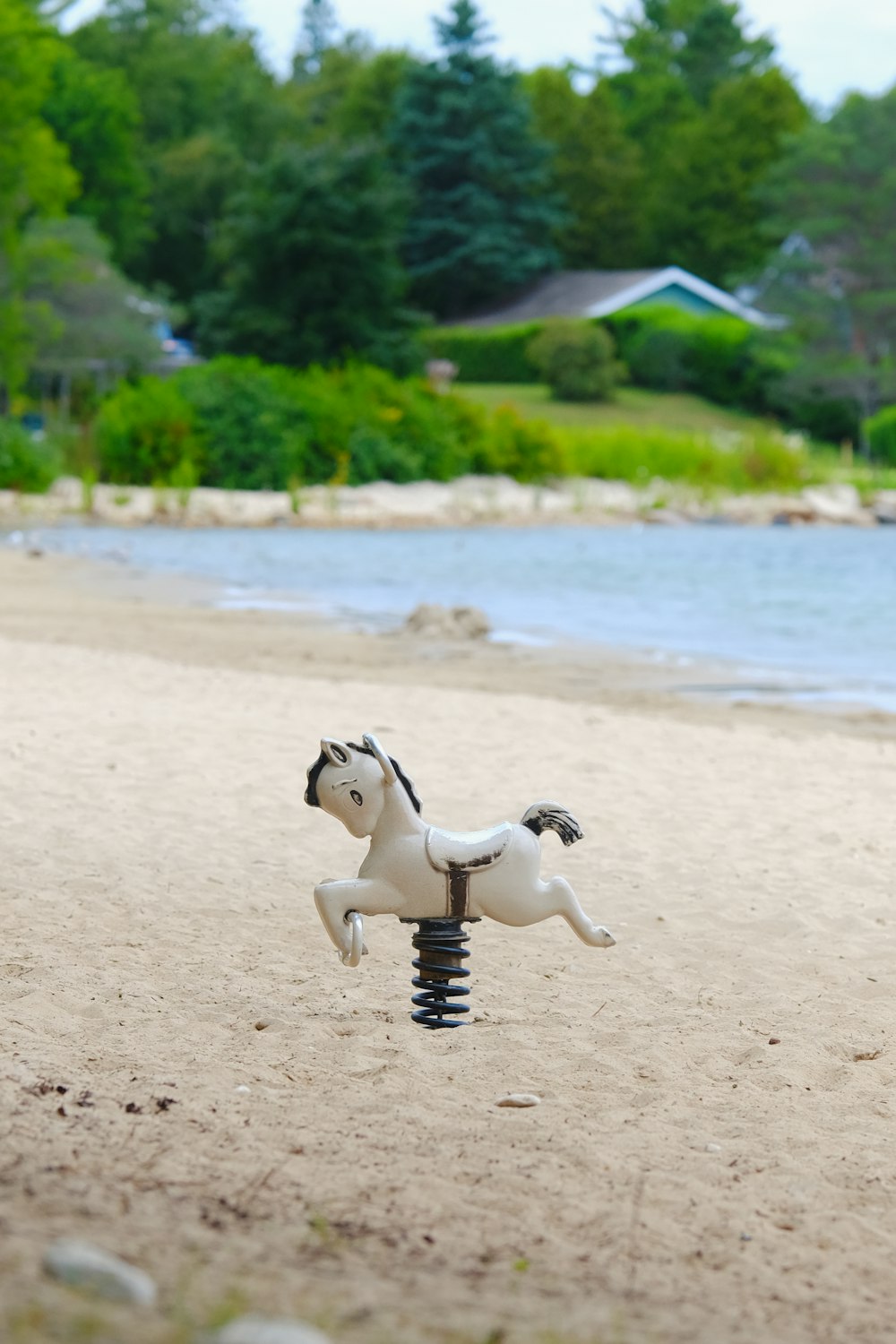 a toy horse is on the beach by the water