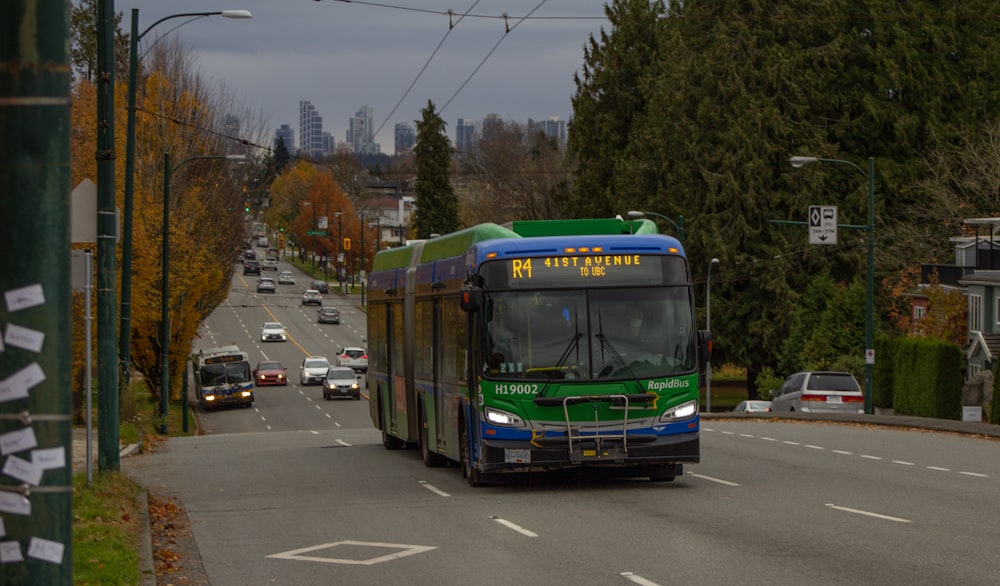 a green and blue bus driving down a street