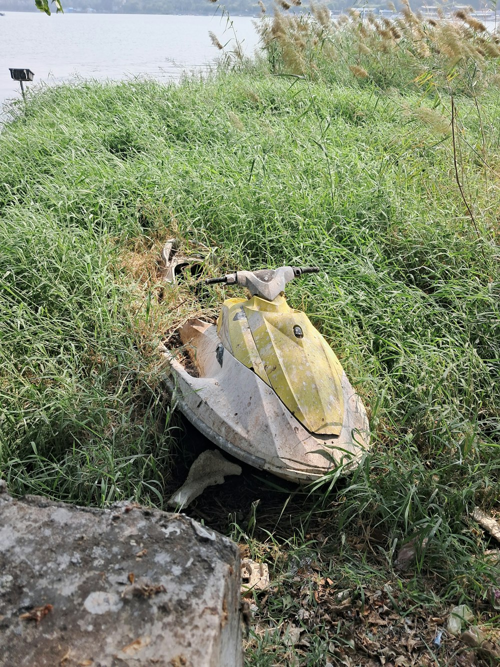 an old, broken out - of - place toy boat in the grass