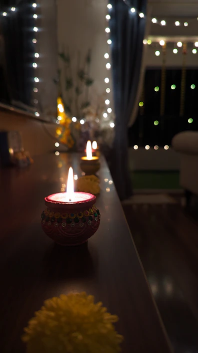A warm-lit traditional Indian lantern hanging in a cozy living room.