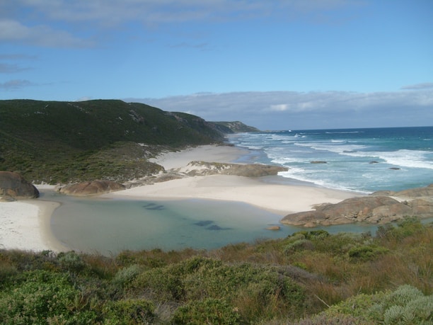 A scenic view of a beautiful beach in Lombok with clear blue waters and soft white sand.