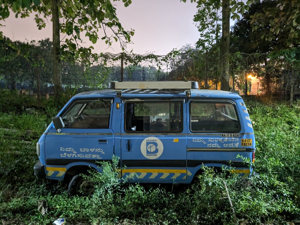 a blue van parked in a field of tall grass