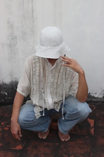 a man sitting on the ground wearing a white hat