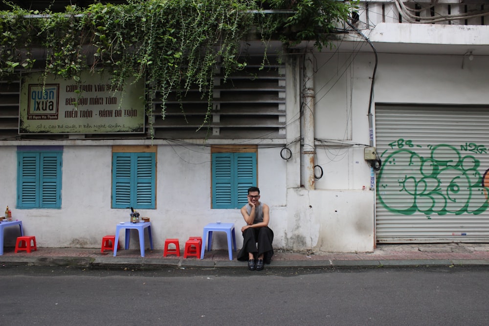 a man sitting on a curb next to a building