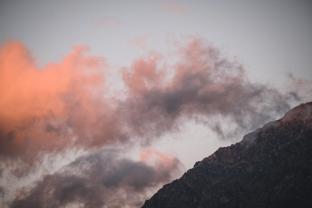 a bird flying in the sky with a mountain in the background