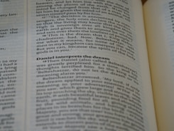 A close-up of an open book, with emphasis on a section discussing Daniel interpreting a dream. The text is in English and the page appears slightly curved.