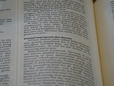 A close-up of an open book, with emphasis on a section discussing Daniel interpreting a dream. The text is in English and the page appears slightly curved.