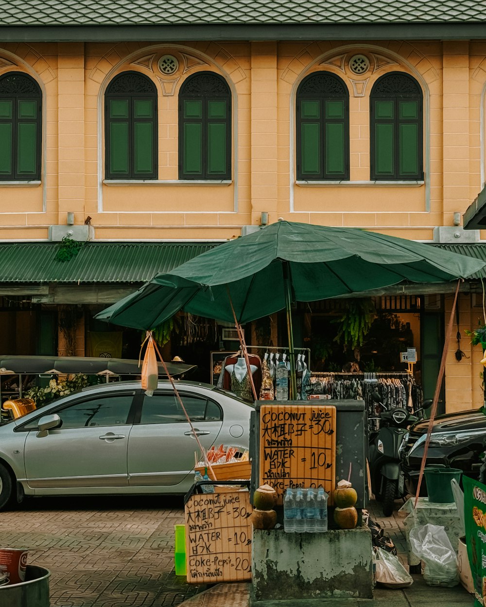 a car parked in front of a building with a green umbrella