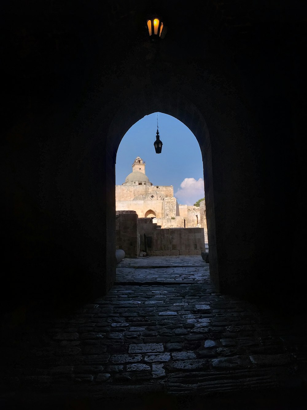 an archway leading to a building with a clock tower in the background