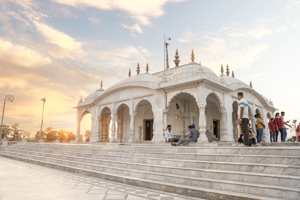 a group of people standing around a white building