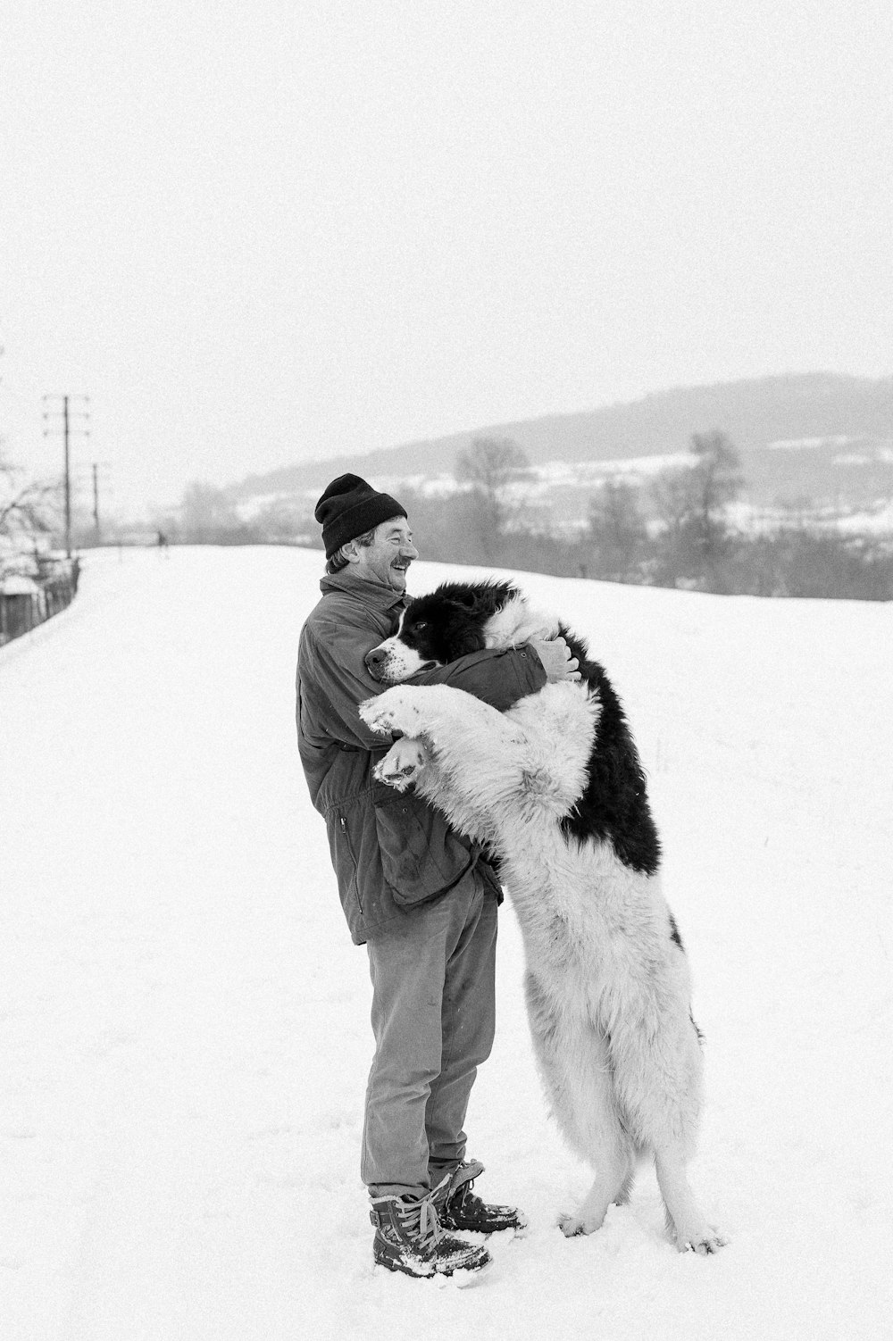 um homem segurando um cachorro na neve