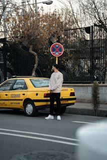a man standing in front of a yellow taxi