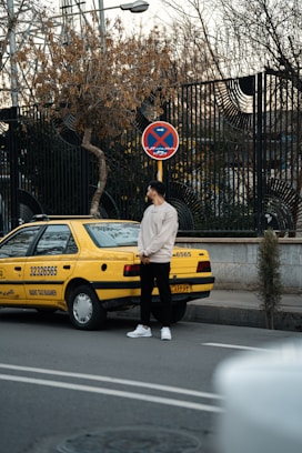 a man standing in front of a yellow taxi