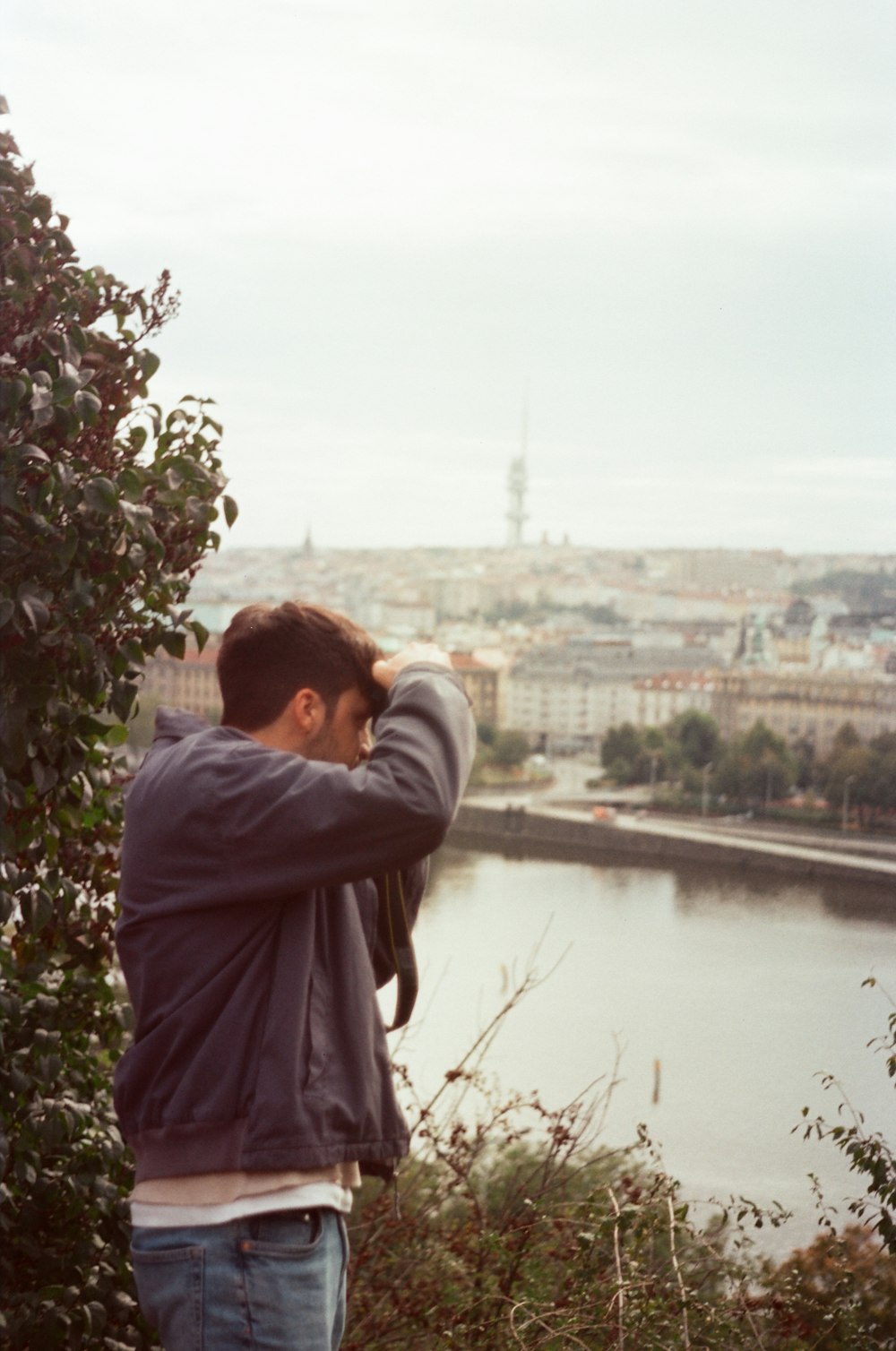 a man standing on top of a hill next to a river