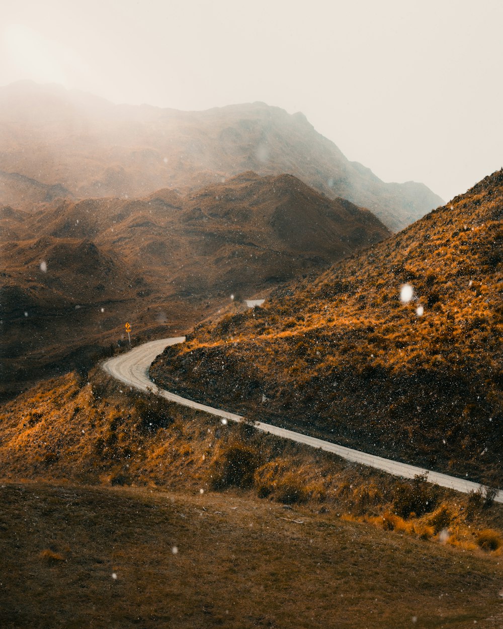 a winding road in the mountains on a foggy day