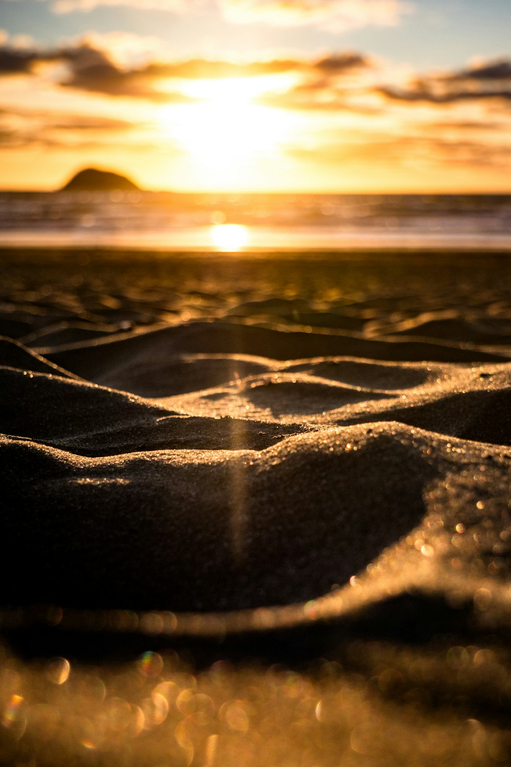 Il sole sta tramontando sulla spiaggia e sulla sabbia
