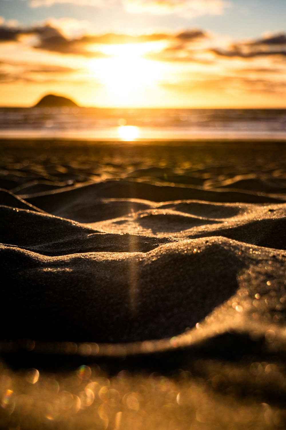 the sun is setting over the beach and sand