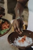 Close-up of hands preparing traditional Mexican mole sauce in a rustic kitchen.