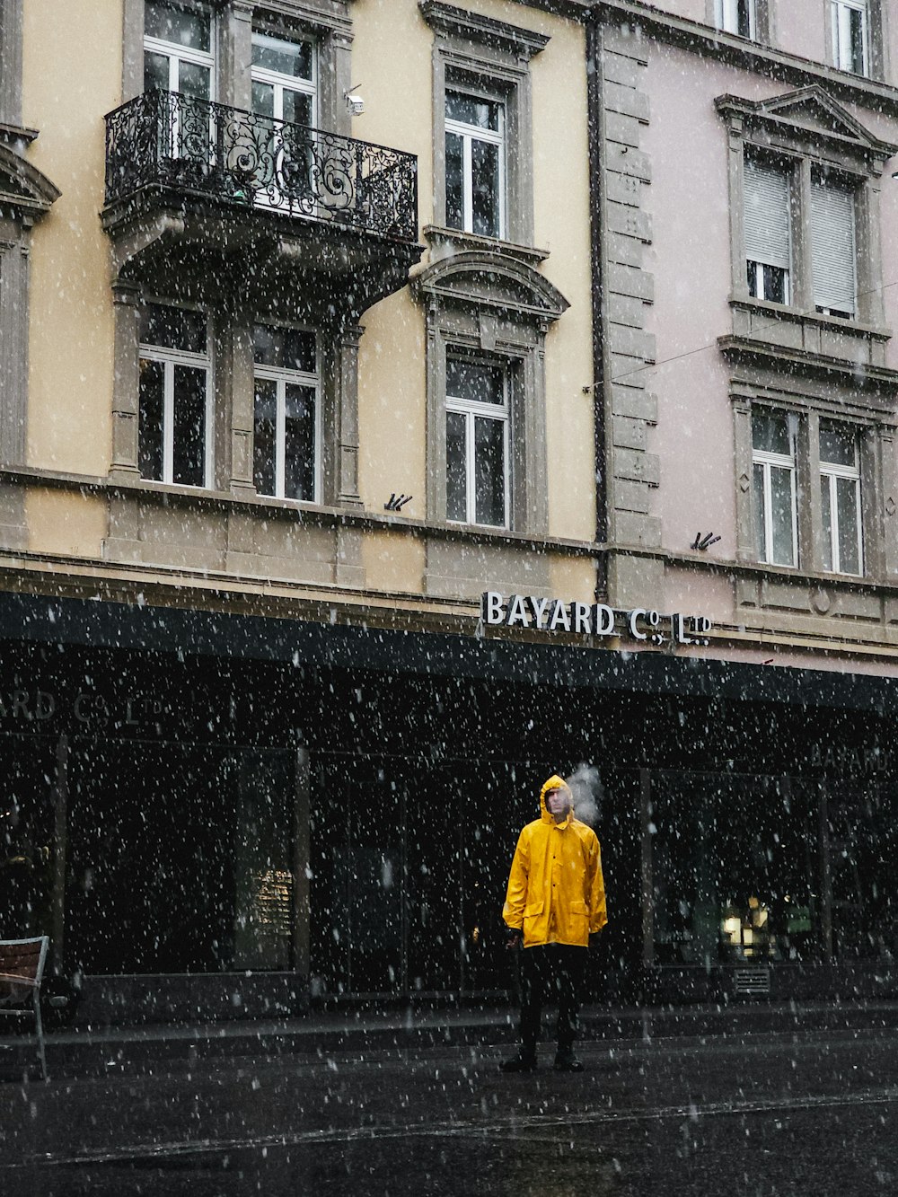 a person in a yellow raincoat standing in front of a building