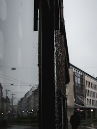 A moody still from a short film showing a lone figure walking through a rainy city street at night.
