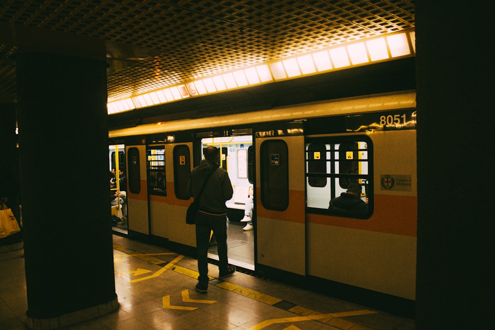 a man standing on a subway platform next to a train