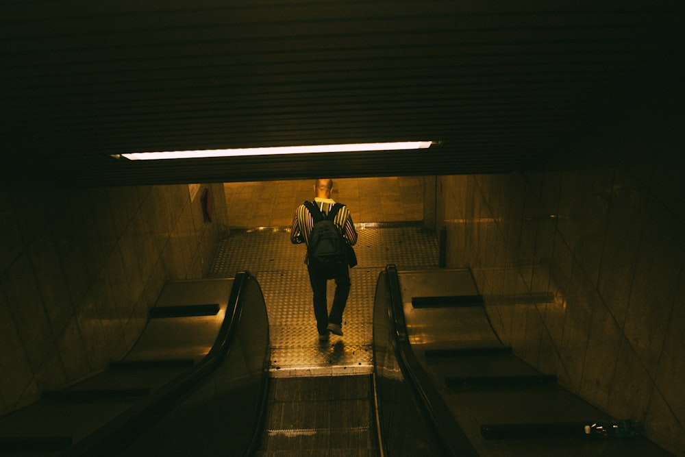 a man is walking down an escalator in the dark