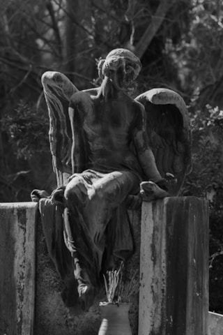 A serene black and white photo of a softly glowing angel statue surrounded by gentle shadows.