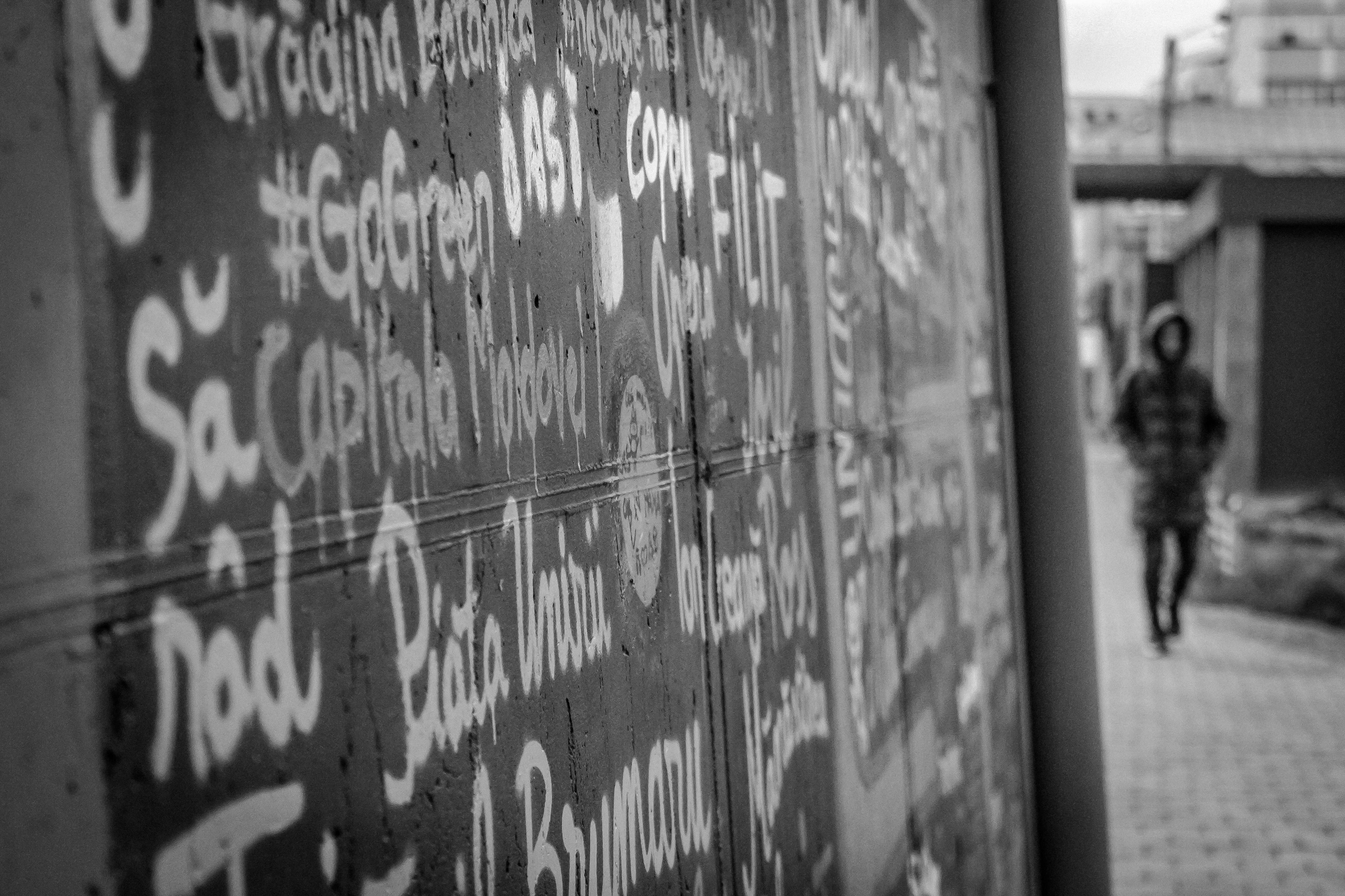 a man walking down a sidewalk next to a wall covered in graffiti