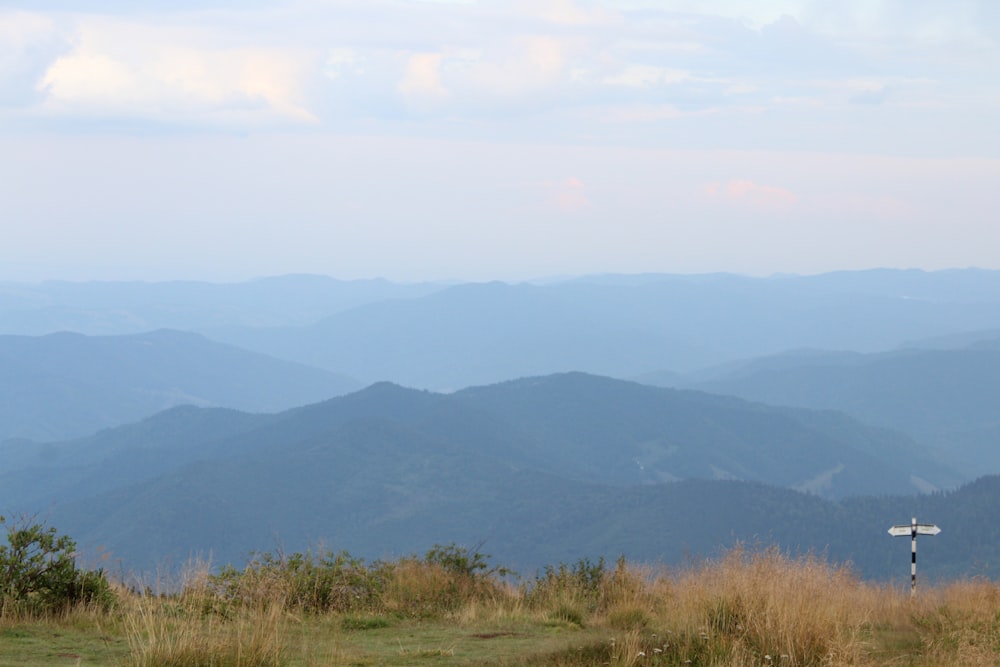 a cross on a grassy hill with mountains in the background